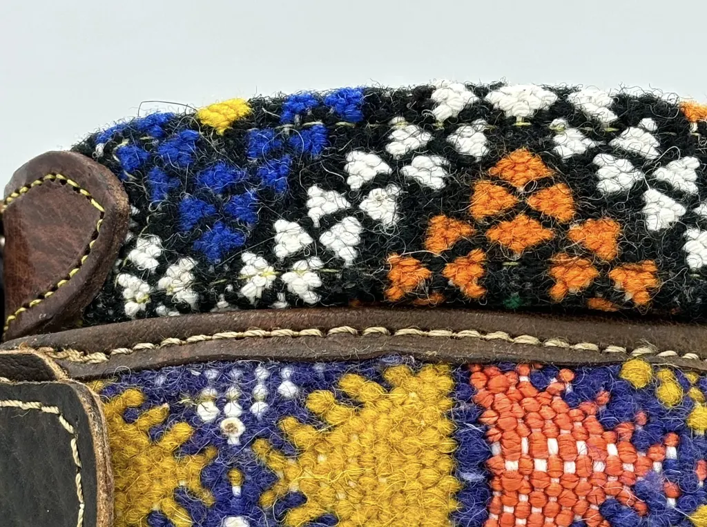 Close-up of hand-woven kilim in black, white, cobalt and orange lattice above a saffron band