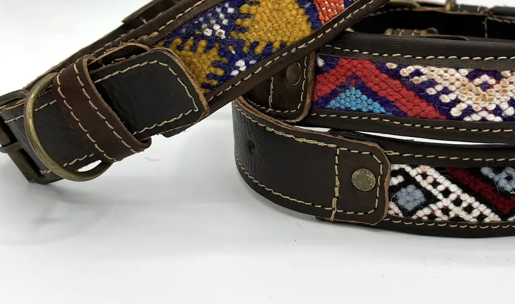 A BohoBarks collar's brass-tone buckle and rivets beside a stack of woven collars