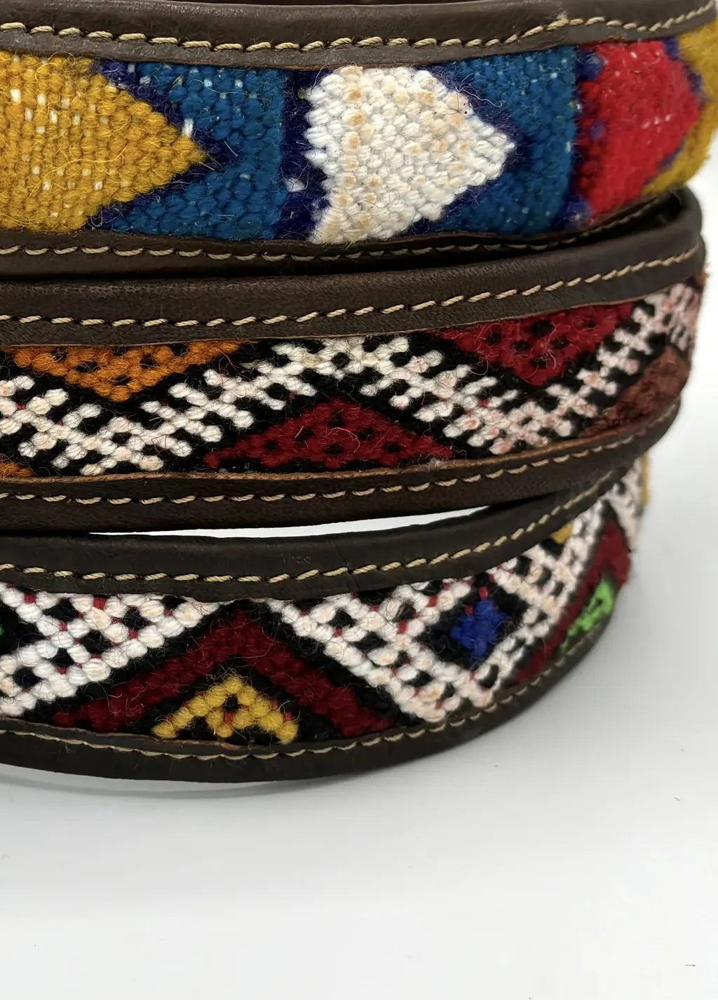 Three stacked BohoBarks collars with saffron, crimson and cream kilim bands in stitched leather