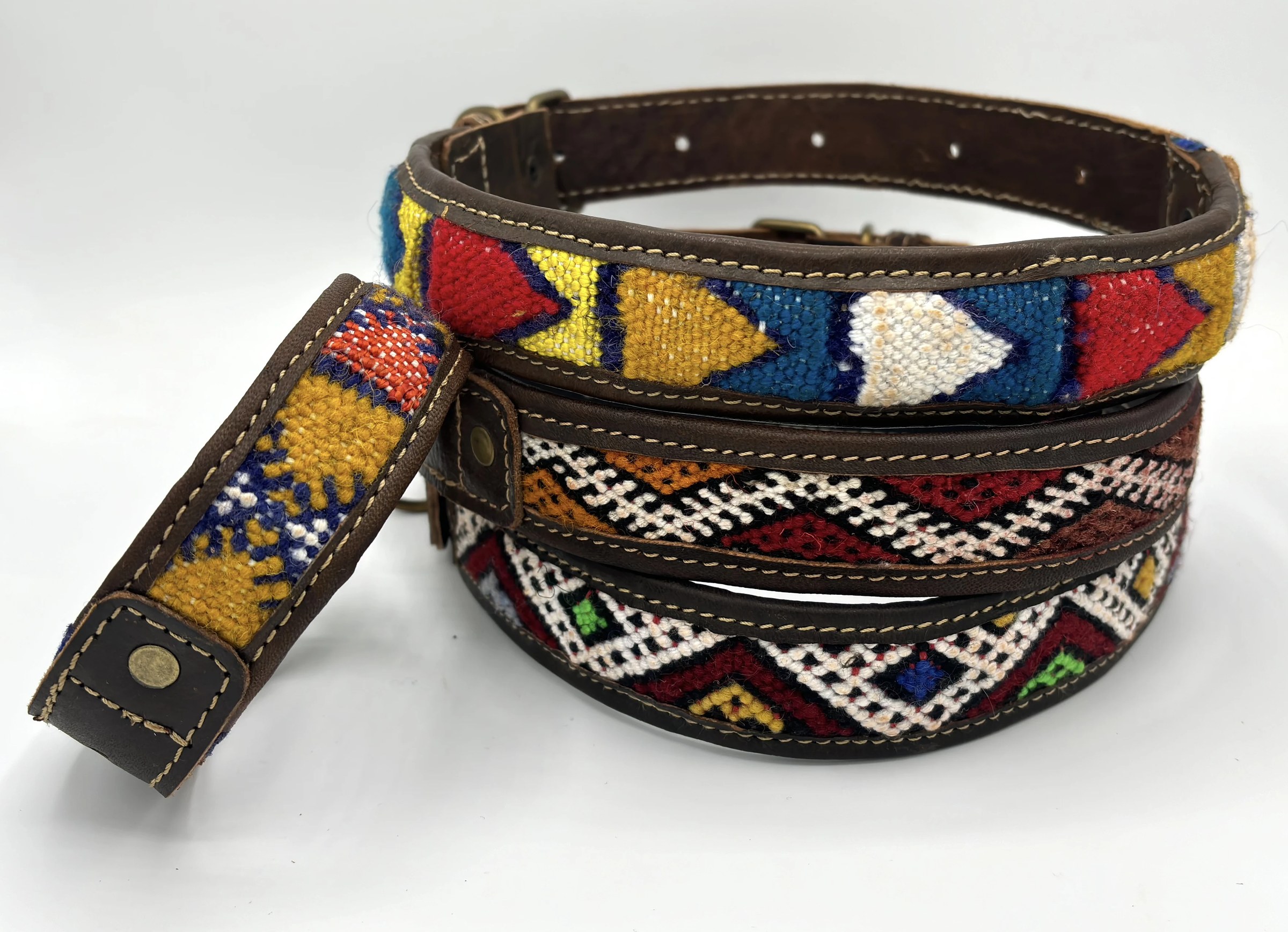 Four BohoBarks collars piled together on a white table, woven fronts facing up