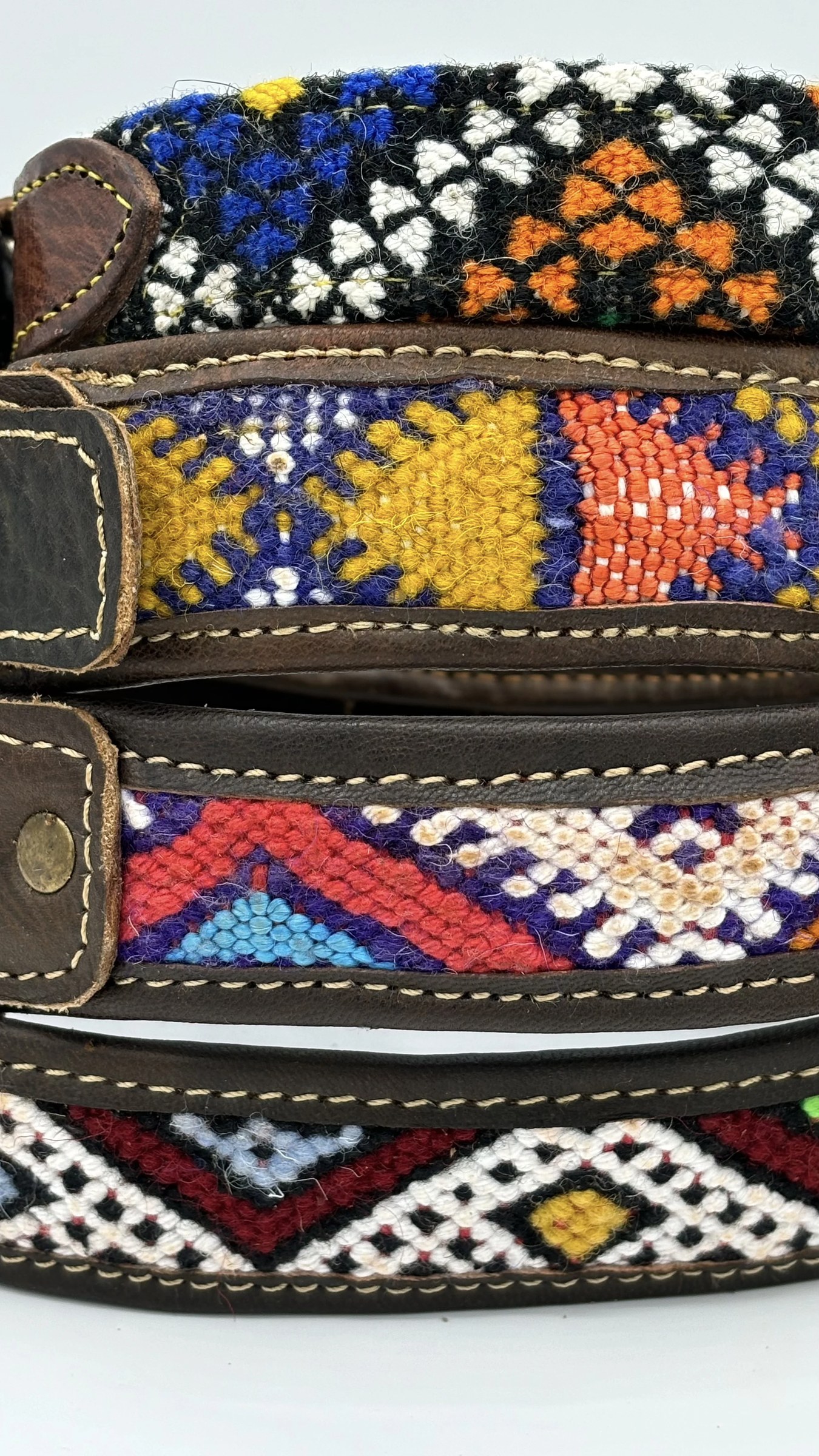 Close vertical view of stacked collars, kilim weave and brass rivets