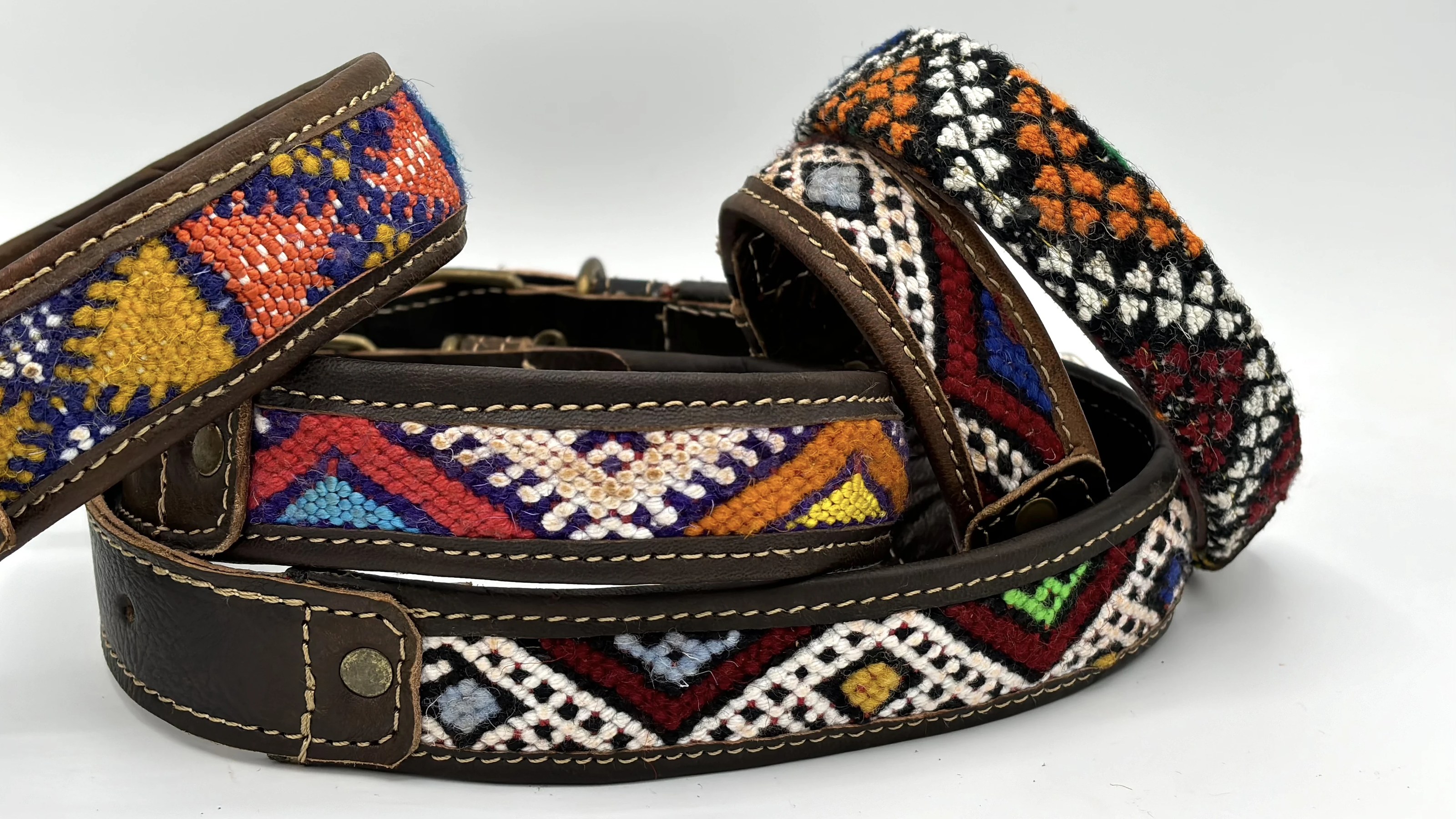 A fanned stack of BohoBarks collars showing their stitched leather edges and woven kilim fronts