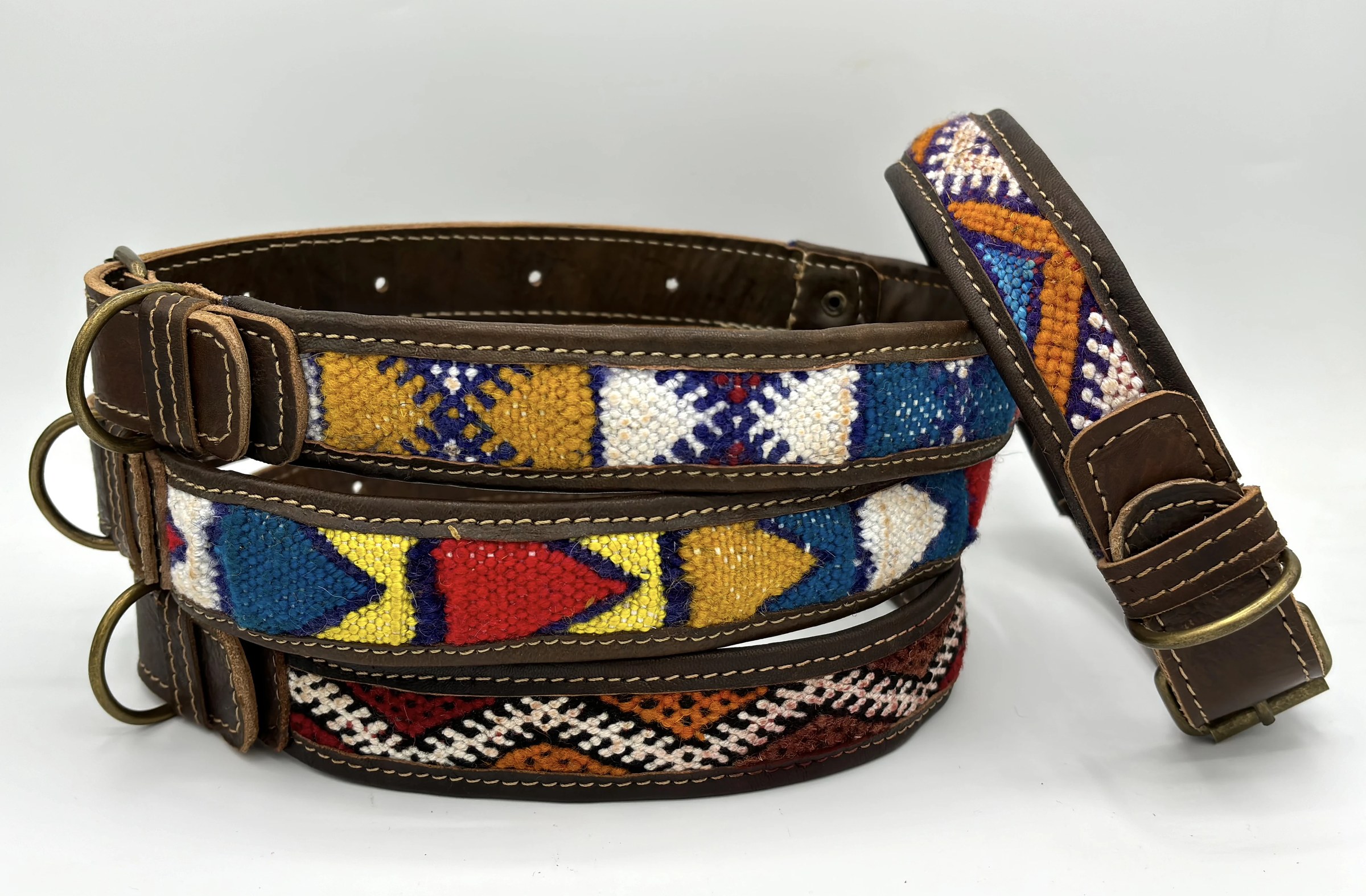 Three collars stacked with a fourth leaning against them, brass D-rings facing out