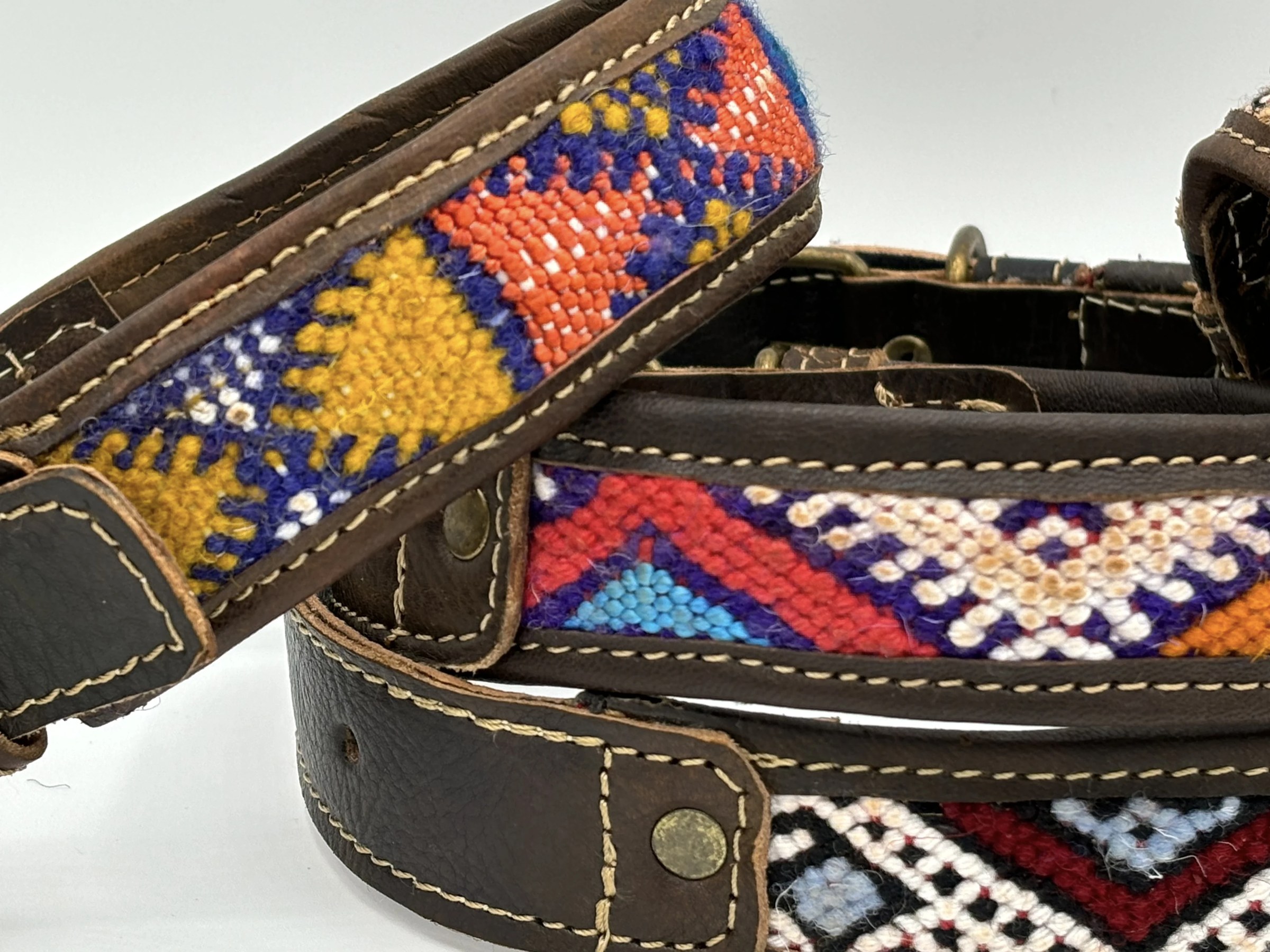 Close-up of hand-woven kilim bands in saffron, coral and cobalt set into stitched leather